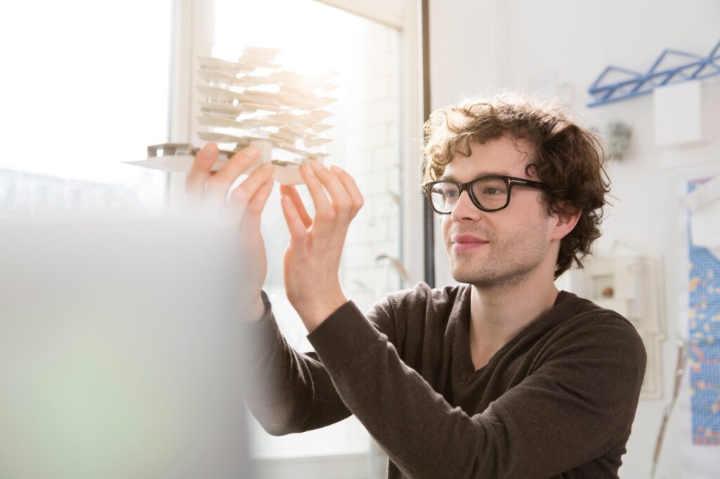 Portrait of young architect looking at architectural model
