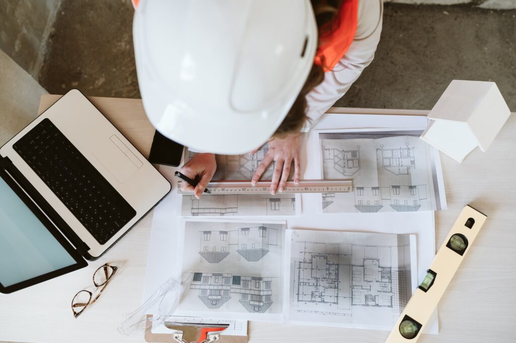 top view of professional architect woman in construction site working on laptop and blueprints