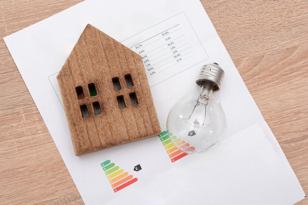Wooden House Model and and light bulb on Energy Efficiency Rating Chart, electricity prices concept